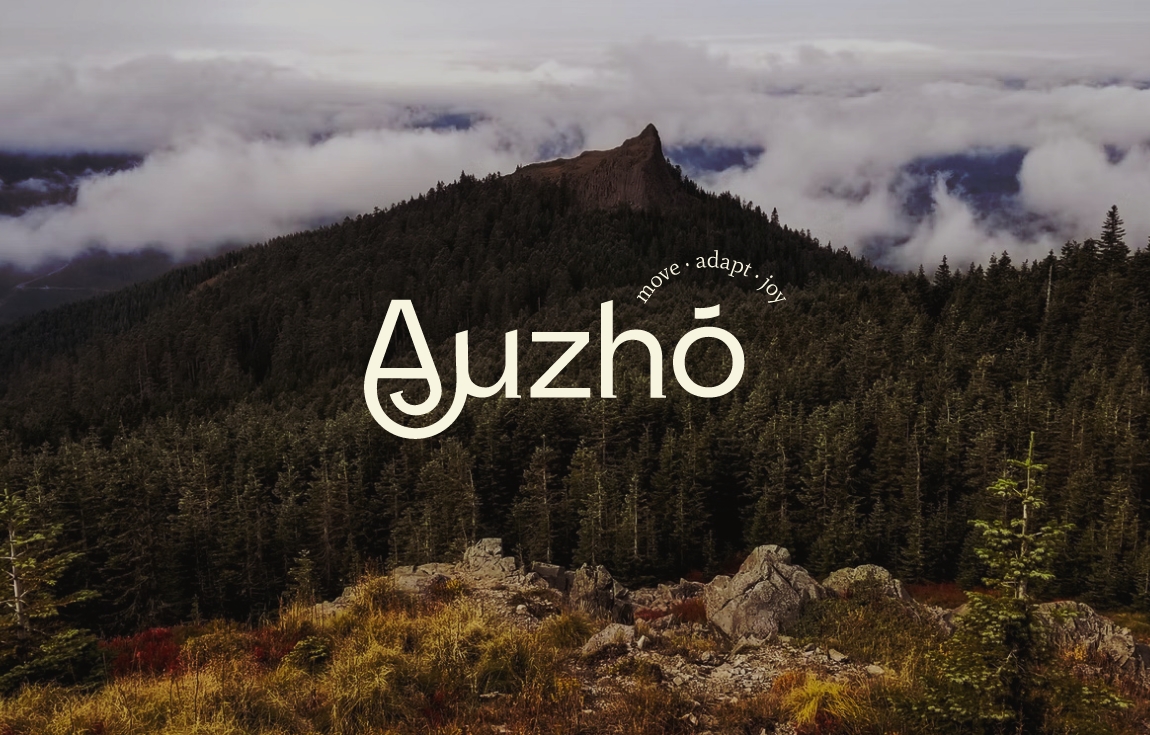logo d’Auzhó, de couleur claire posé au centre d’une photo de montagne. Le A du logo s’enroule sur lui-même comme un escargot et s’attache au u à sa gauche. Les couleurs de la photo sont automnales.